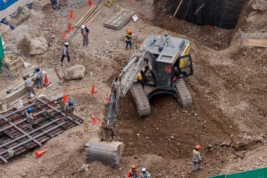 Sarı bir kazıcı, gücünü ve hassasiyetini kullanarak yüksek bir yapının gelecekteki temelini kazıyor. Gücün, ilerlemenin ve her büyük yapının arkasındaki enerjinin sembolü..