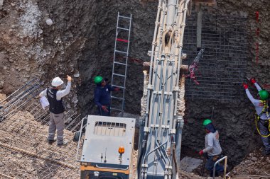 İnşaat işçileri temeli hassasiyet ve güçle güçlendiriyor. Her hareket yeteneği, güvenliği ve kendini adamayı yansıtır. Daha büyük bir şeyin yükselişi için temel oluşturur..