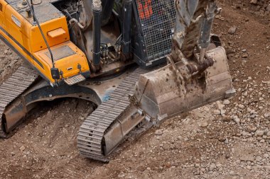 Sarı bir kazıcı, gücünü ve hassasiyetini kullanarak yüksek bir yapının gelecekteki temelini kazıyor. Gücün, ilerlemenin ve her büyük yapının arkasındaki enerjinin sembolü..