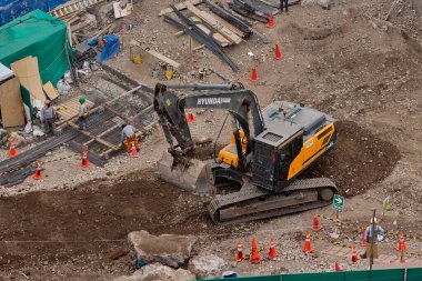 Sarı bir kazıcı, gücünü ve hassasiyetini kullanarak yüksek bir yapının gelecekteki temelini kazıyor. Gücün, ilerlemenin ve her büyük yapının arkasındaki enerjinin sembolü..