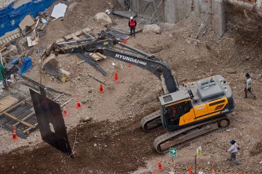 Sarı bir kazıcı, gücünü ve hassasiyetini kullanarak yüksek bir yapının gelecekteki temelini kazıyor. Gücün, ilerlemenin ve her büyük yapının arkasındaki enerjinin sembolü..