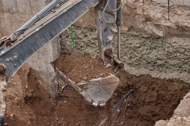 Kazı kovası inşaat sırasında toprağı kazıyor, güç, hassasiyet ve ağır makineleri iş başında gösteriyor..