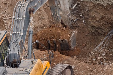 Kazı kovası inşaat sırasında toprağı kazıyor, güç, hassasiyet ve ağır makineleri iş başında gösteriyor..
