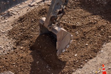 Kazı kovası inşaat sırasında toprağı kazıyor, güç, hassasiyet ve ağır makineleri iş başında gösteriyor..