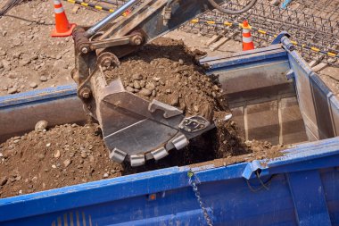 Kazı kovası inşaat sırasında toprağı kazıyor, güç, hassasiyet ve ağır makineleri iş başında gösteriyor..