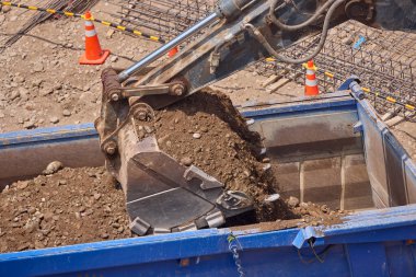 Kazı kovası inşaat sırasında toprağı kazıyor, güç, hassasiyet ve ağır makineleri iş başında gösteriyor..