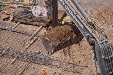 Kazı kovası inşaat sırasında toprağı kazıyor, güç, hassasiyet ve ağır makineleri iş başında gösteriyor..