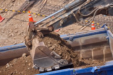 Kazı kovası inşaat sırasında toprağı kazıyor, güç, hassasiyet ve ağır makineleri iş başında gösteriyor..