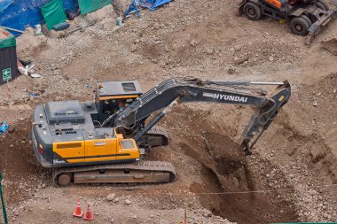 Hidrolik kazıcı aktif bir inşaat sahasında temel çalışması sırasında bir çöp kamyonuna toprak yüklerken ağır makineler iş başında,