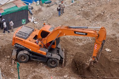 Hidrolik kazıcı aktif bir inşaat sahasında temel çalışması sırasında bir çöp kamyonuna toprak yüklerken ağır makineler iş başında,