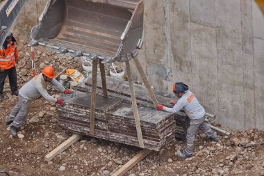 İnşaat işçileri temeli hassasiyet ve güçle güçlendiriyor. Her hareket yeteneği, güvenliği ve kendini adamayı yansıtır. Daha büyük bir şeyin yükselişi için temel oluşturur..