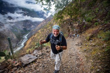Bir grup yürüyüşçü Choquequirao 'ya doğru bir dağ yolu boyunca yürüyorlar, etrafları sis, sarp kayalıklar ve And bitkileriyle çevrili..