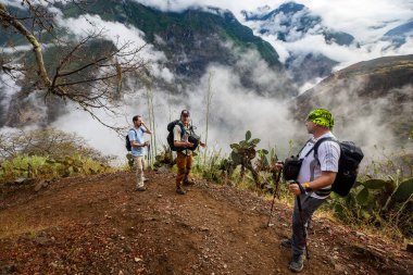 Bir grup yürüyüşçü Choquequirao 'ya doğru bir dağ yolu boyunca yürüyorlar, etrafları sis, sarp kayalıklar ve And bitkileriyle çevrili..