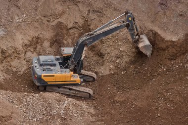 İnşaat alanında kazı yapan kazıcı, zemin ve temel hazırlıkları sırasında toprak ve kayaları hareket ettirdi..