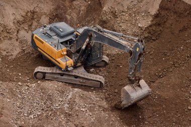 İnşaat alanında kazı yapan kazıcı, zemin ve temel hazırlıkları sırasında toprak ve kayaları hareket ettirdi..