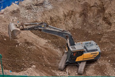 İnşaat alanında kazı yapan kazıcı, zemin ve temel hazırlıkları sırasında toprak ve kayaları hareket ettirdi..