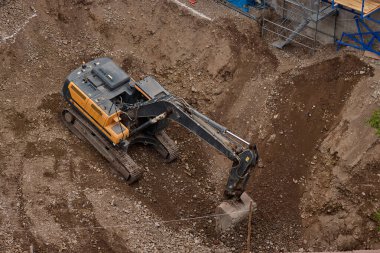 İnşaat alanında kazı yapan kazıcı, zemin ve temel hazırlıkları sırasında toprak ve kayaları hareket ettirdi..