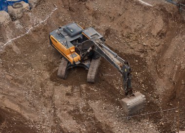 İnşaat alanında kazı yapan kazıcı, zemin ve temel hazırlıkları sırasında toprak ve kayaları hareket ettirdi..