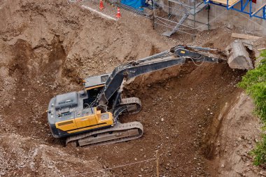 İnşaat alanında kazı yapan kazıcı, zemin ve temel hazırlıkları sırasında toprak ve kayaları hareket ettirdi..