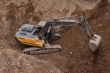 İnşaat alanında kazı yapan kazıcı, zemin ve temel hazırlıkları sırasında toprak ve kayaları hareket ettirdi..