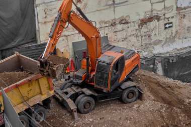 Sarı Kazıcı bir inşaat alanında kazı yapıyor, zemin ve temel hazırlıkları sırasında toprak ve kayaları hareket ettiriyor..