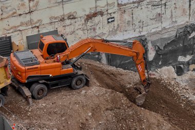 Sarı Kazıcı bir inşaat alanında kazı yapıyor, zemin ve temel hazırlıkları sırasında toprak ve kayaları hareket ettiriyor..