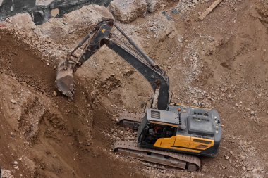 İnşaat alanında kazı yapan kazıcı, zemin ve temel hazırlıkları sırasında toprak ve kayaları hareket ettirdi..