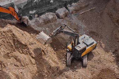 İnşaat alanında kazı yapan kazıcı, zemin ve temel hazırlıkları sırasında toprak ve kayaları hareket ettirdi..