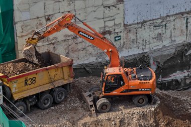Toprak ve kaya katmanlarını eşeleyen bir kazıcı aktif bir inşaat projesinin temelini hazırlamak için hareketlerini koordine ediyor..