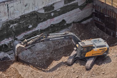 Sarı Kazıcı bir inşaat alanında kazı yapıyor, zemin ve temel hazırlıkları sırasında toprak ve kayaları hareket ettiriyor..