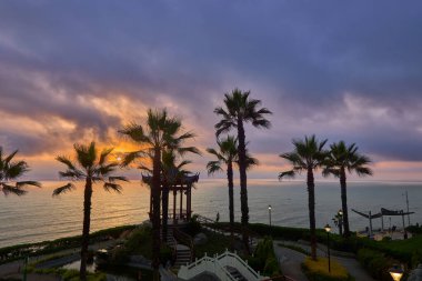 Miraflores 'deki Parque Chino' da gün batımı, Limasilhouetted palmiyeleri ve Pasifik 'i çevreleyen geleneksel bir pavyon, altın ışığın sessizce denizin üzerine çöktüğü ve şehrin akşama doğru nefes verdiği yer..