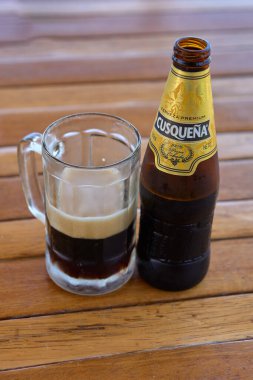 Deniz tarafından içilen buz gibi bir bira, Peru güneşinin altındaki arka planda altın kum ve turkuaz sularla birlikte sade bir sahil zevki.