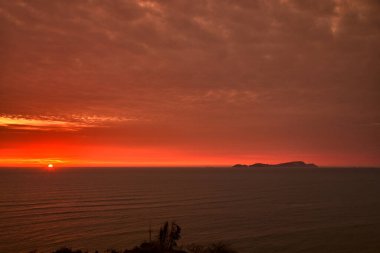 San Lorenzo adası dramatik bir günbatımında, Lima. Peru 'nun en büyük adası olan San Lorenzo, Callao takımadasının önemli bir parçasıdır ve Lima' nın Malecn adasında yürüyenler için ufukta sürekli bir mevcudiyet bulunmaktadır..