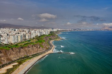 Miraflores 'in havadan bakış açısı, Lima. Bu manzara, modern şehrin ufuk çizgisi ile Pasifik Okyanusu 'yla buluşan La Costa Verde' nin engebeli uçurumları arasındaki dramatik zıtlığı yakalar. Aşağıda, 'Circuito de Playas' karayolu kıyı boyunca esiyor.
