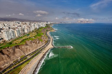 Miraflores 'in havadan bakış açısı, Lima. Bu manzara, modern şehrin ufuk çizgisi ile Pasifik Okyanusu 'yla buluşan La Costa Verde' nin engebeli uçurumları arasındaki dramatik zıtlığı yakalar. Aşağıda, 'Circuito de Playas' karayolu kıyı boyunca esiyor.