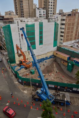 Bir kazıcı havada asılı kalmış, yüksek katlı bir bina projesi için kentsel inşaatın arkasındaki ham gücü, hassasiyeti ve riski yakalıyor..