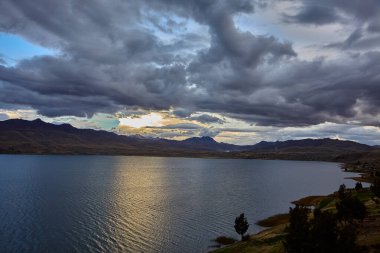 Cusco 'nun Espinar kenti yakınlarındaki Canas ilinde bulunan Langui Layo lagünü, parlak bir gökyüzü ve beyaz bulutları yansıtan derin mavi sulara sahip. Çevresindeki And manzarası altın dağlık araziler, küçük kırsal yerleşim alanları ve bir arkaplan