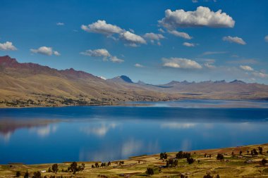 Cusco 'nun Espinar kenti yakınlarındaki Canas ilinde bulunan Langui Layo lagünü, parlak bir gökyüzü ve beyaz bulutları yansıtan derin mavi sulara sahip. Çevresindeki And manzarası altın dağlık araziler, küçük kırsal yerleşim alanları ve bir arkaplan