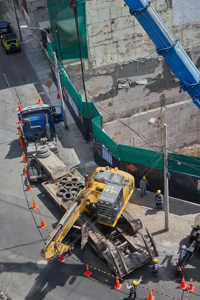 Ağır vinç kazıcıyı şehir ortamında derin bir inşaat sahasına kaldırıyor, altyapı geliştirme, gayrimenkul büyümesi ve modern şehir genişlemesi sergiliyor..