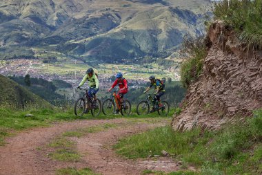 Peru, Cusco 'da antik dağlık patikalar boyunca seyahat eden bir grup dağ bisikletçisi, otantik yerel kültür, tarihi manzaralar ve uzak bir And ortamında aktif bir yaşam tarzı ve keşif ruhunu yansıtan açık hava maceraları yaşıyorlar..