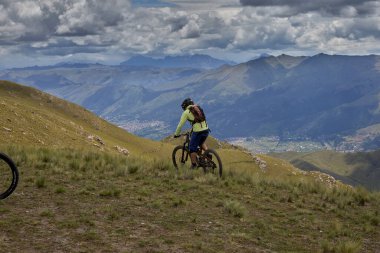 Peru, Cusco 'da antik dağlık patikalar boyunca seyahat eden bir grup dağ bisikletçisi, otantik yerel kültür, tarihi manzaralar ve uzak bir And ortamında aktif bir yaşam tarzı ve keşif ruhunu yansıtan açık hava maceraları yaşıyorlar..