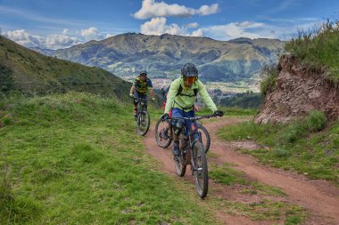 Peru, Cusco 'da antik dağlık patikalar boyunca seyahat eden bir grup dağ bisikletçisi, otantik yerel kültür, tarihi manzaralar ve uzak bir And ortamında aktif bir yaşam tarzı ve keşif ruhunu yansıtan açık hava maceraları yaşıyorlar..