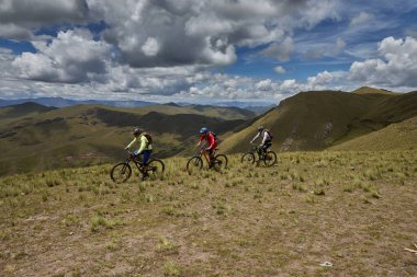 Peru, Cusco 'da antik dağlık patikalar boyunca seyahat eden bir grup dağ bisikletçisi, otantik yerel kültür, tarihi manzaralar ve uzak bir And ortamında aktif bir yaşam tarzı ve keşif ruhunu yansıtan açık hava maceraları yaşıyorlar..