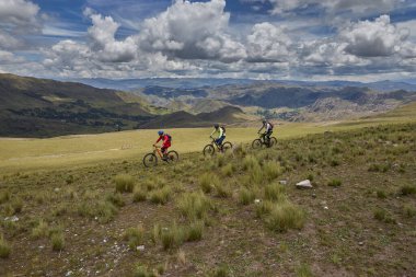 Peru, Cusco 'da antik dağlık patikalar boyunca seyahat eden bir grup dağ bisikletçisi, otantik yerel kültür, tarihi manzaralar ve uzak bir And ortamında aktif bir yaşam tarzı ve keşif ruhunu yansıtan açık hava maceraları yaşıyorlar..