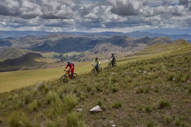 Peru, Cusco 'da antik dağlık patikalar boyunca seyahat eden bir grup dağ bisikletçisi, otantik yerel kültür, tarihi manzaralar ve uzak bir And ortamında aktif bir yaşam tarzı ve keşif ruhunu yansıtan açık hava maceraları yaşıyorlar..
