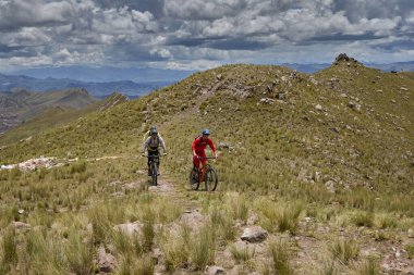 Peru, Cusco 'da antik dağlık patikalar boyunca seyahat eden bir grup dağ bisikletçisi, otantik yerel kültür, tarihi manzaralar ve uzak bir And ortamında aktif bir yaşam tarzı ve keşif ruhunu yansıtan açık hava maceraları yaşıyorlar..