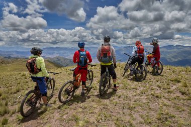 Peru, Cusco 'da antik dağlık patikalar boyunca seyahat eden bir grup dağ bisikletçisi, otantik yerel kültür, tarihi manzaralar ve uzak bir And ortamında aktif bir yaşam tarzı ve keşif ruhunu yansıtan açık hava maceraları yaşıyorlar..