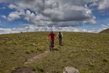 Peru, Cusco 'da antik dağlık patikalar boyunca seyahat eden bir grup dağ bisikletçisi, otantik yerel kültür, tarihi manzaralar ve uzak bir And ortamında aktif bir yaşam tarzı ve keşif ruhunu yansıtan açık hava maceraları yaşıyorlar..