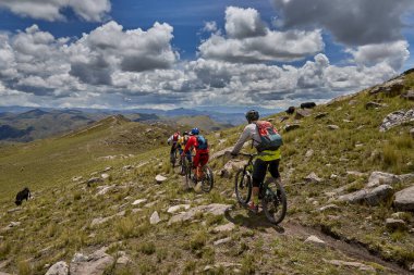 Peru, Cusco 'da antik dağlık patikalar boyunca seyahat eden bir grup dağ bisikletçisi, otantik yerel kültür, tarihi manzaralar ve uzak bir And ortamında aktif bir yaşam tarzı ve keşif ruhunu yansıtan açık hava maceraları yaşıyorlar..