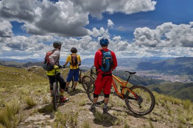 Peru, Cusco 'da antik dağlık patikalar boyunca seyahat eden bir grup dağ bisikletçisi, otantik yerel kültür, tarihi manzaralar ve uzak bir And ortamında aktif bir yaşam tarzı ve keşif ruhunu yansıtan açık hava maceraları yaşıyorlar..